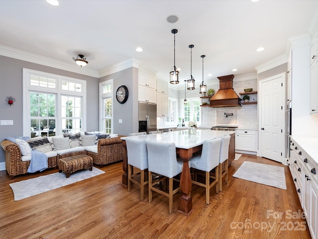 1509 Churchill Downs Dr, Waxhaw, NC 28173 - kitchen with custom range hood, stainless steel refrigerator with ice dispenser, light wood-style floors, light countertops, and crown molding