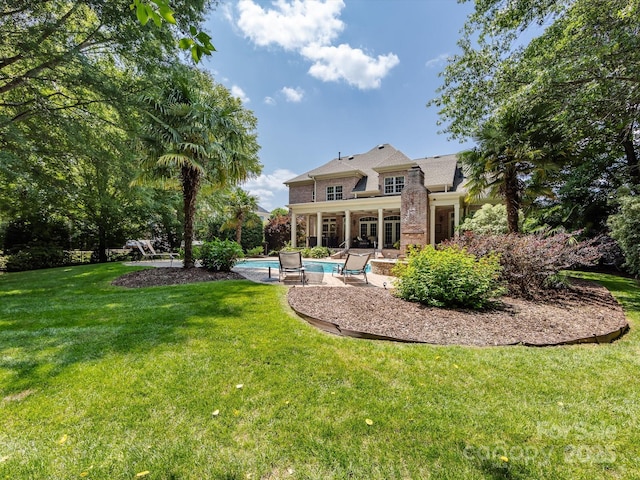 1509 Churchill Downs Dr, Waxhaw, NC 28173 - rear view of house with an outdoor pool, brick siding, a patio, and a lawn