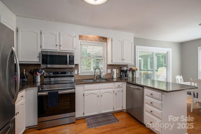 107 Ingonish Dr, Gastonia, NC 28056 - kitchen featuring stainless steel appliances, a sink, a peninsula, white cabinetry, and backsplash