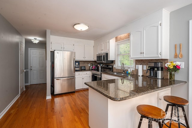 107 Ingonish Dr, Gastonia, NC 28056 - kitchen featuring appliances with stainless steel finishes, a sink, a peninsula, light wood-type flooring, and white cabinetry
