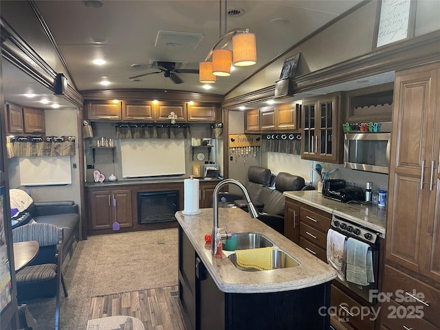 5400 Little River Neck Rd Unit 169, North Myrtle Beach, SC 29582 - kitchen featuring stainless steel microwave, a sink, a ceiling fan, oven, and a center island with sink