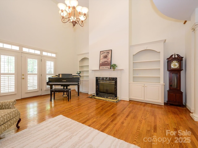 1209 S S St, Gastonia, NC 28052 - living room featuring a high ceiling, built in shelves, a chandelier, a fireplace, and light wood finished floors