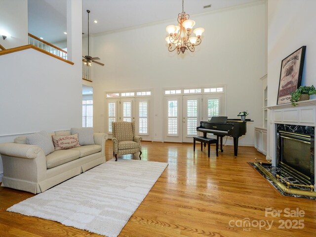 1209 S S St, Gastonia, NC 28052 - living room featuring a ceiling fan, a high ceiling, a chandelier, a fireplace, and light wood-style flooring