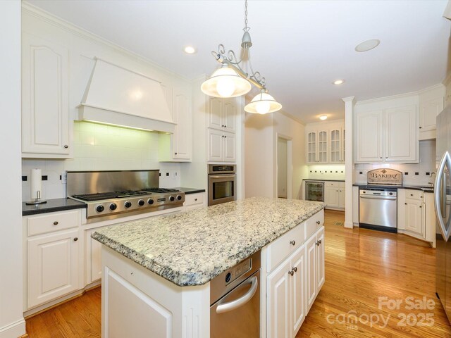 1209 S S St, Gastonia, NC 28052 - kitchen featuring stainless steel appliances, custom range hood, backsplash, white cabinets, and a kitchen island