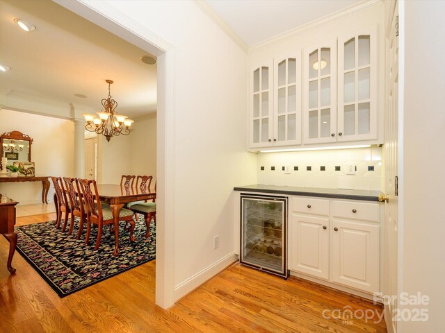 1209 S S St, Gastonia, NC 28052 - indoor dry bar with beverage cooler, crown molding, light wood-type flooring, a chandelier, and tasteful backsplash