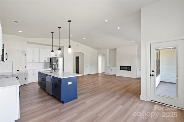 8632 Cedarbrook Dr, Charlotte, NC 28215 - kitchen featuring stainless steel appliances, a sink, arched walkways, blue cabinetry, and white cabinets