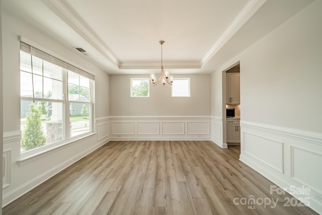 113 Summerhill Dr, Mooresville, NC 28115 - unfurnished dining area featuring a tray ceiling, a chandelier, light wood-style floors, crown molding, and a wainscoted wall