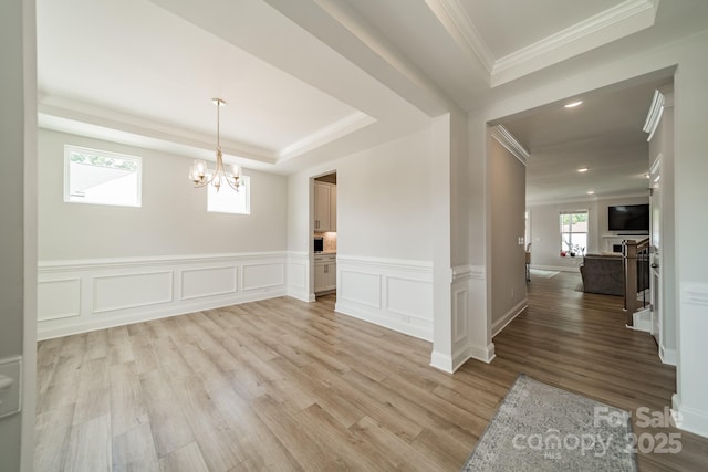 113 Summerhill Dr, Mooresville, NC 28115 - unfurnished dining area with a tray ceiling, ornamental molding, light wood-style flooring, a chandelier, and wainscoting