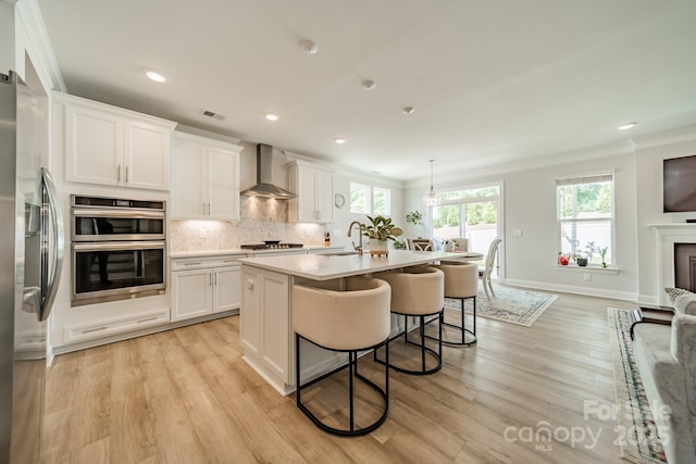 113 Summerhill Dr, Mooresville, NC 28115 - kitchen with wall chimney exhaust hood, ornamental molding, a sink, appliances with stainless steel finishes, and light wood-type flooring