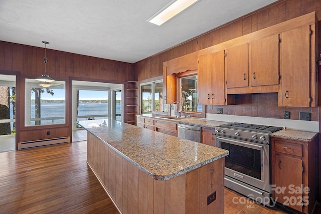 392 Stonemarker Rd, Mooresville, NC 28117 - kitchen with appliances with stainless steel finishes, a baseboard radiator, a sink, wood walls, and a kitchen island