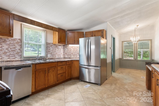 4648 Rifle Range Rd, Conover, NC 28613 - kitchen featuring stainless steel appliances, a sink, vaulted ceiling, brown cabinets, and plenty of natural light