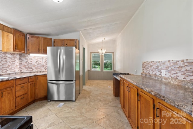 4648 Rifle Range Rd, Conover, NC 28613 - kitchen featuring freestanding refrigerator, brown cabinets, a chandelier, decorative backsplash, and vaulted ceiling