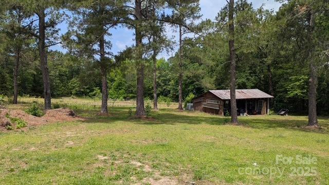 187 Cartledge Creek Rd, Rockingham, NC 28379 - view of green lawn featuring a wooded view, a pole building, and an outdoor structure