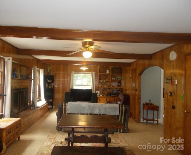 187 Cartledge Creek Rd, Rockingham, NC 28379 - living area with wooden walls, beam ceiling, arched walkways, a ceiling fan, and a brick fireplace