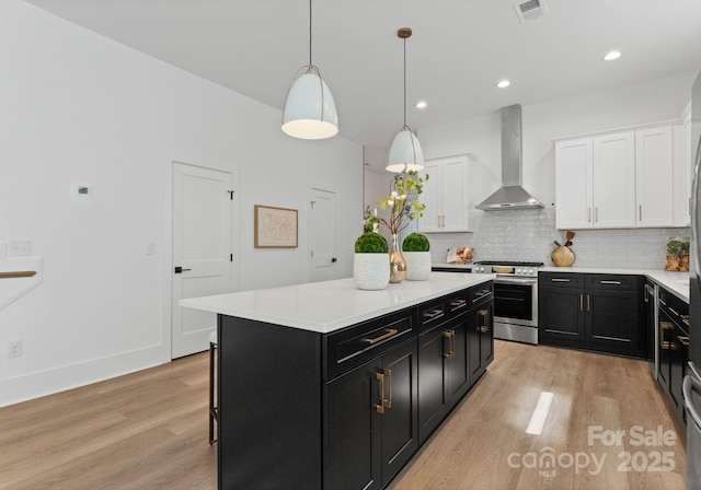 2004 St John St, Charlotte, NC 28216 - kitchen with stainless steel range with gas cooktop, wall chimney range hood, dark cabinets, white cabinets, and light wood-style floors
