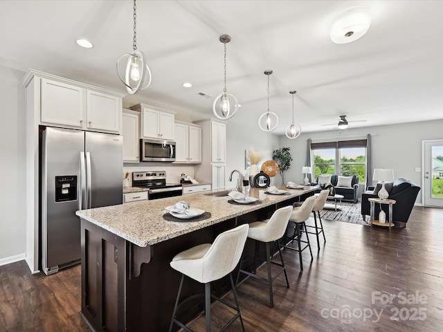 2017 New Hope Branch Way, Belmont, NC 28012 - kitchen featuring appliances with stainless steel finishes, a sink, dark wood finished floors, white cabinetry, and a kitchen bar