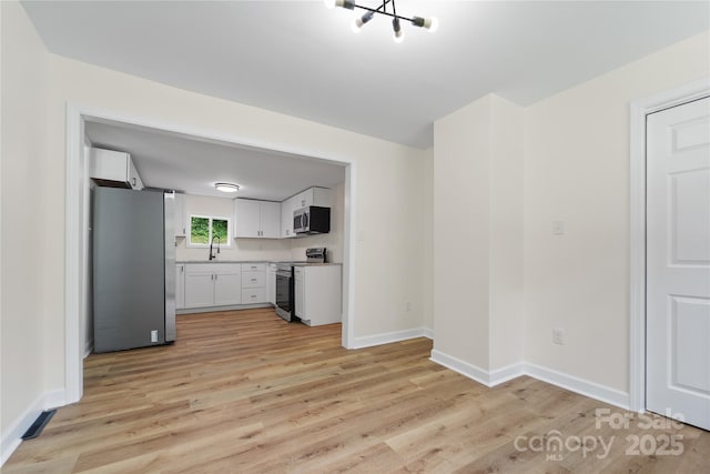 94 Camp Branch Rd, Black Mountain, NC 28711 - kitchen with stainless steel appliances, light wood-style flooring, white cabinets, and light countertops