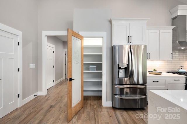 9 Robey Dr, Fletcher, NC 28732 - kitchen with appliances with stainless steel finishes, wood finished floors, white cabinets, backsplash, and wall chimney exhaust hood