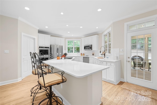 763 Evans Manor Dr, Weddington, NC 28104 - kitchen with stainless steel appliances, a sink, crown molding, light wood-type flooring, and a kitchen breakfast bar