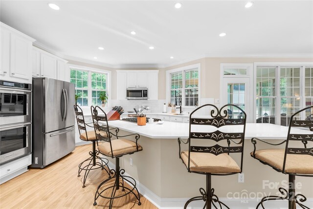 763 Evans Manor Dr, Weddington, NC 28104 - kitchen with appliances with stainless steel finishes, a breakfast bar, ornamental molding, white cabinetry, and backsplash