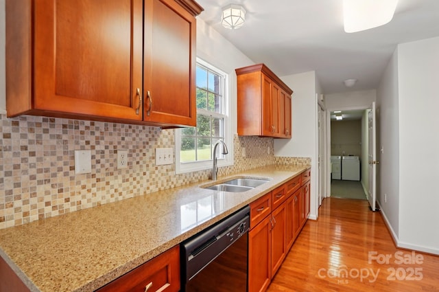 924 Secrest Hill Dr, Monroe, NC 28110 - kitchen featuring black dishwasher, washing machine and dryer, a sink, light wood-style floors, and light stone counters