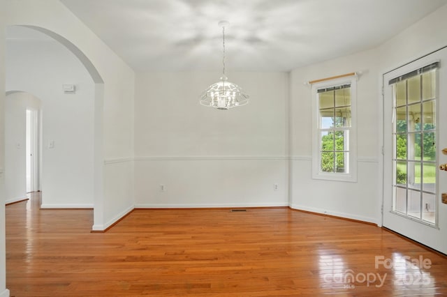 924 Secrest Hill Dr, Monroe, NC 28110 - unfurnished dining area with arched walkways, light wood finished floors, a chandelier, and baseboards