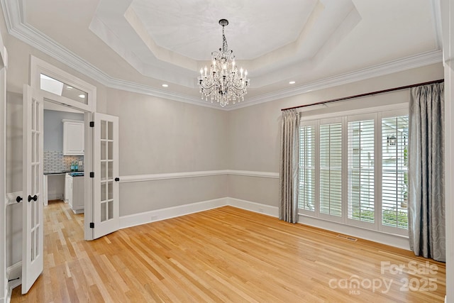 17308 Players Ridge Dr, Cornelius, NC 28031 - spare room with french doors, a chandelier, light wood finished floors, a tray ceiling, and crown molding