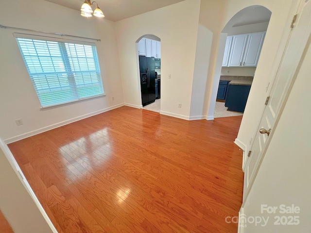 11624 Truan Ln, Cornelius, NC 28031 - empty room featuring arched walkways, light wood finished floors, baseboards, and a chandelier
