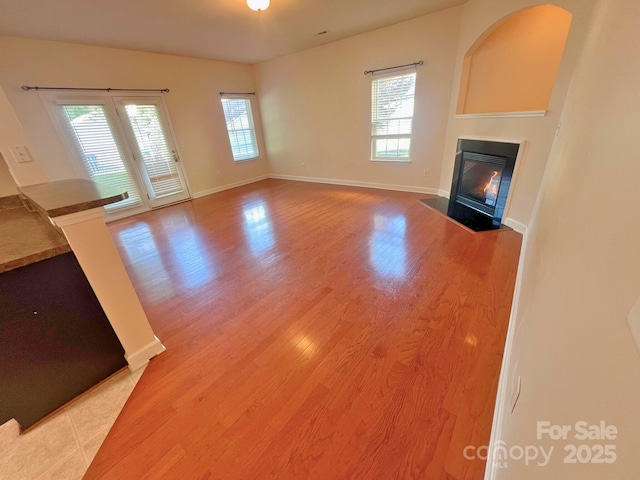 11624 Truan Ln, Cornelius, NC 28031 - unfurnished living room featuring a fireplace with flush hearth, plenty of natural light, light wood-style flooring, and baseboards