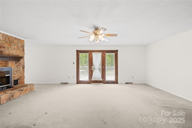 2309 Potter Rd S, Waxhaw, NC 28173 - unfurnished living room with carpet floors, ceiling fan, a stone fireplace, a textured ceiling, and baseboards
