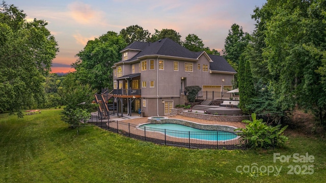 2006 Sandy Pond Ln, Waxhaw, NC 28173 - back of house at dusk with stairs, an in-ground hot tub, a deck, a patio, and stucco siding
