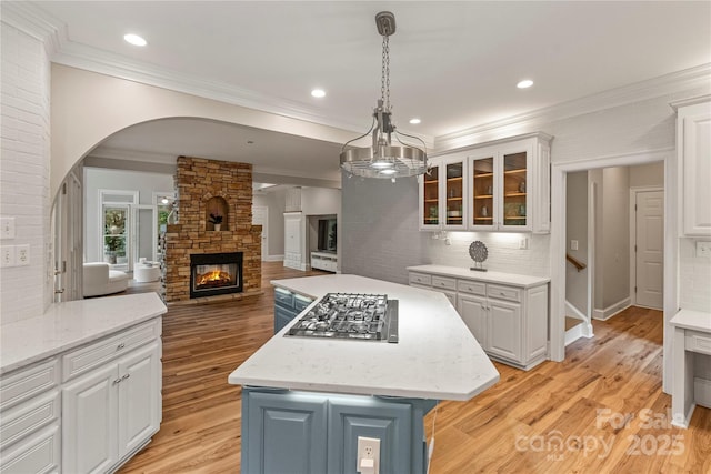 2006 Sandy Pond Ln, Waxhaw, NC 28173 - kitchen featuring stainless steel gas cooktop, open floor plan, white cabinets, a kitchen island, and ornamental molding