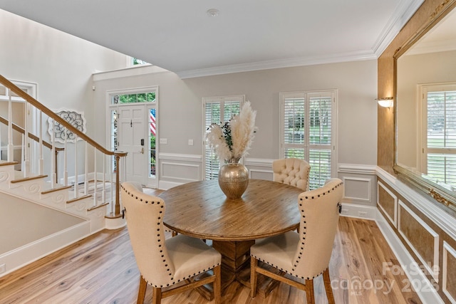 2006 Sandy Pond Ln, Waxhaw, NC 28173 - dining space featuring crown molding, a decorative wall, light wood-type flooring, stairs, and a wainscoted wall