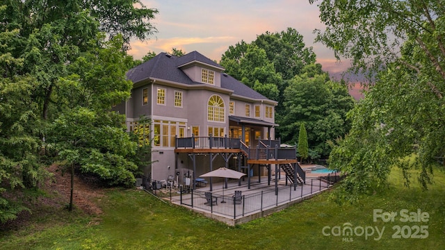 2006 Sandy Pond Ln, Waxhaw, NC 28173 - back of house at dusk featuring a patio, a wooden deck, stairs, stucco siding, and a yard