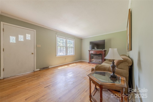 5840 Potter Rd, Matthews, NC 28104 - living area with ornamental molding, light wood finished floors, a glass covered fireplace, and baseboards