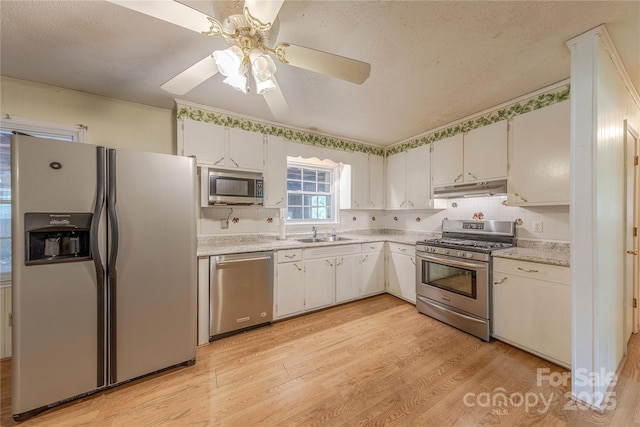 5840 Potter Rd, Matthews, NC 28104 - kitchen with stainless steel appliances, light countertops, under cabinet range hood, a sink, and light wood finished floors