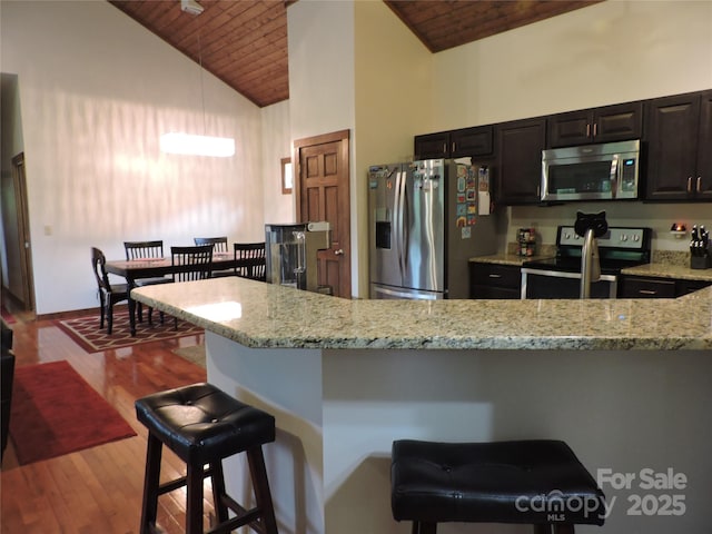 235 Red Oak Ln, Burnsville, NC 28714 - kitchen featuring stainless steel appliances, wood ceiling, light stone counters, high vaulted ceiling, and a breakfast bar area