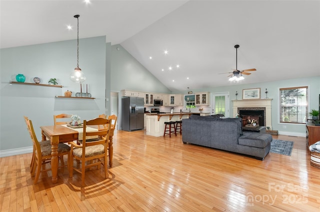 20 Grove Garden Ave, Candler, NC 28715 - dining space with ceiling fan, light wood-type flooring, a fireplace, high vaulted ceiling, and baseboards