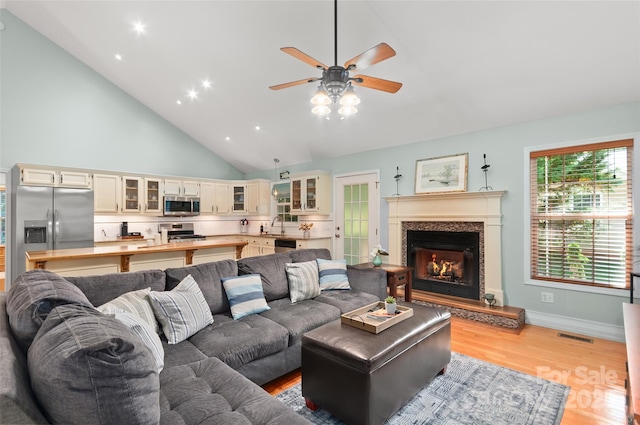 20 Grove Garden Ave, Candler, NC 28715 - living room with ceiling fan, light wood-type flooring, a lit fireplace, high vaulted ceiling, and baseboards