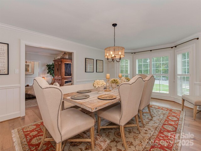 4201 Quail Hunt Ln, Charlotte, NC 28226 - dining room featuring ornamental molding, a chandelier, light wood-style floors, a decorative wall, and a wainscoted wall