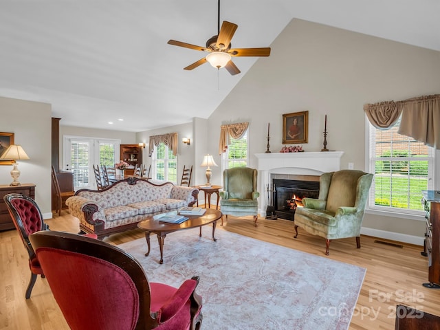 116 Memphis Way, Spindale, NC 28160 - living room featuring ceiling fan, a glass covered fireplace, baseboards, light wood-type flooring, and high vaulted ceiling