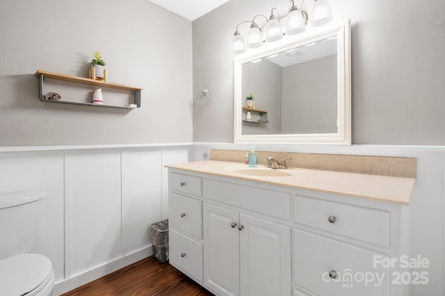 1525 16th Avenue Cir NW, Hickory, NC 28601 - bathroom with toilet, vanity, a wainscoted wall, wood finished floors, and a decorative wall