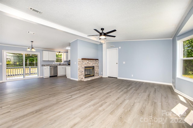 4750 Enochville Rd, Kannapolis, NC 28081 - unfurnished living room featuring a textured ceiling, light wood finished floors, a stone fireplace, baseboards, and a ceiling fan