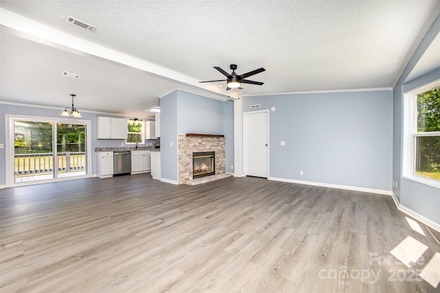 4750 Enochville Rd, Kannapolis, NC 28081 - unfurnished living room featuring a textured ceiling, light wood-type flooring, a stone fireplace, baseboards, and ornamental molding