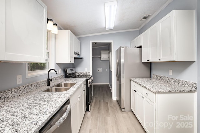 4750 Enochville Rd, Kannapolis, NC 28081 - kitchen with appliances with stainless steel finishes, a sink, white cabinets, light wood-style flooring, and crown molding