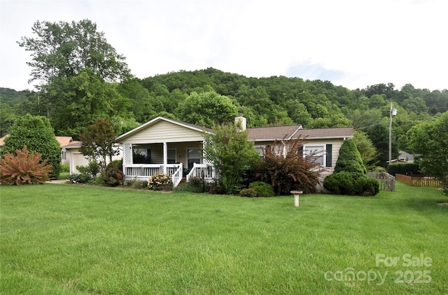 74 Sunflower Ln, Waynesville, NC 28785 - ranch-style house featuring a porch, a front yard, a chimney, and a wooded view