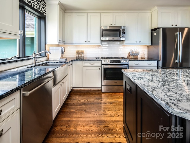 4344 Eagles Nest Rd, Waynesville, NC 28786 - kitchen with stainless steel appliances, a sink, dark stone countertops, white cabinetry, and backsplash