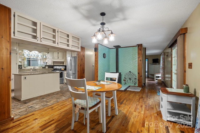 14518 Big Laurel Rd, Mars Hill, NC 28754 - dining space featuring light wood finished floors, a chandelier, a textured ceiling, and a wood stove