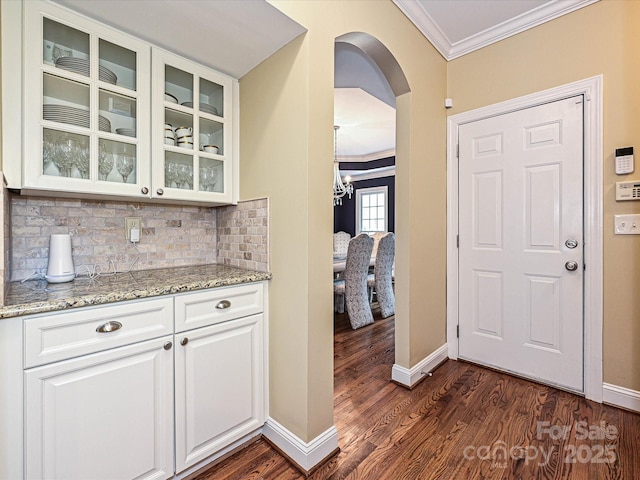 2406 Tarleton Twins Ter, Charlotte, NC 28270 - bar area with crown molding, baseboards, arched walkways, dark wood-style floors, and tasteful backsplash