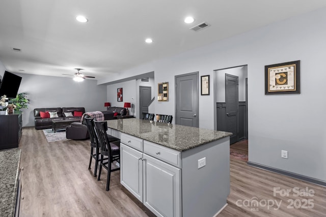 1725 Mill Creek Ln SW, Concord, NC 28025 - kitchen with a kitchen bar, a ceiling fan, white cabinetry, a center island, and light wood-style floors